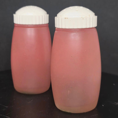 Back view of vintage Bartlett Collins pink frosted glass shakers showing plastic lids