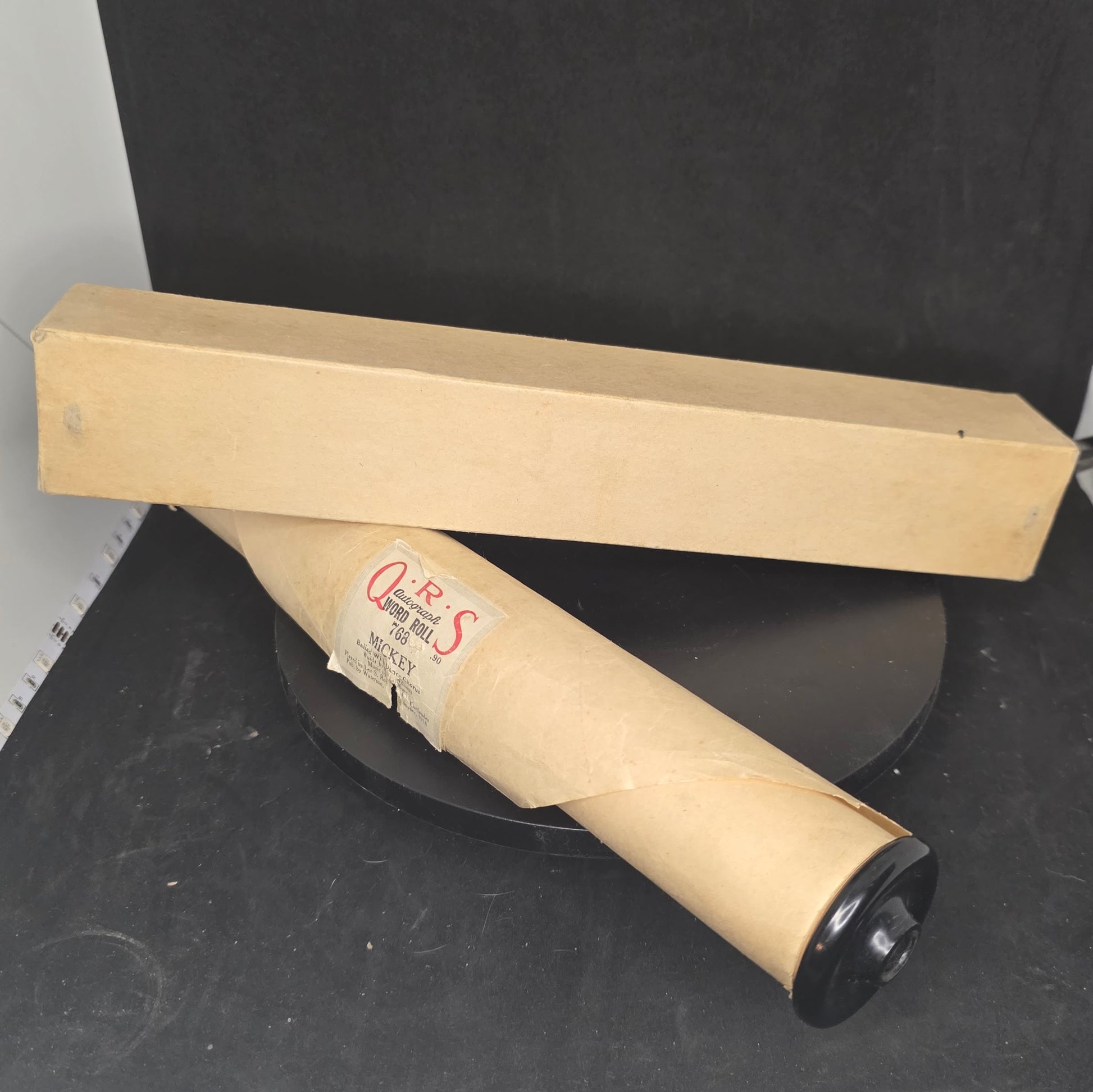 Q.R.S MICKEY piano roll partially displayed showing aged perforated paper and Bakelite end cap construction