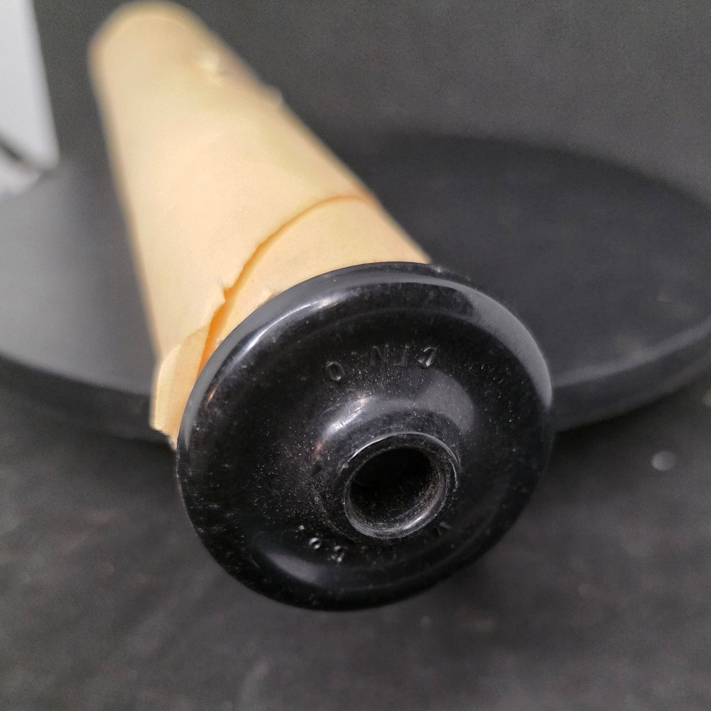 Close-up of black Bakelite flanged end cap on vintage Q.R.S MICKEY piano roll showing authentic period hardware