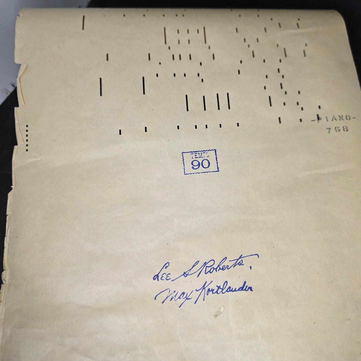 Q.R.S MICKEY piano roll partially displayed showing aged perforated paper and Bakelite end cap construction