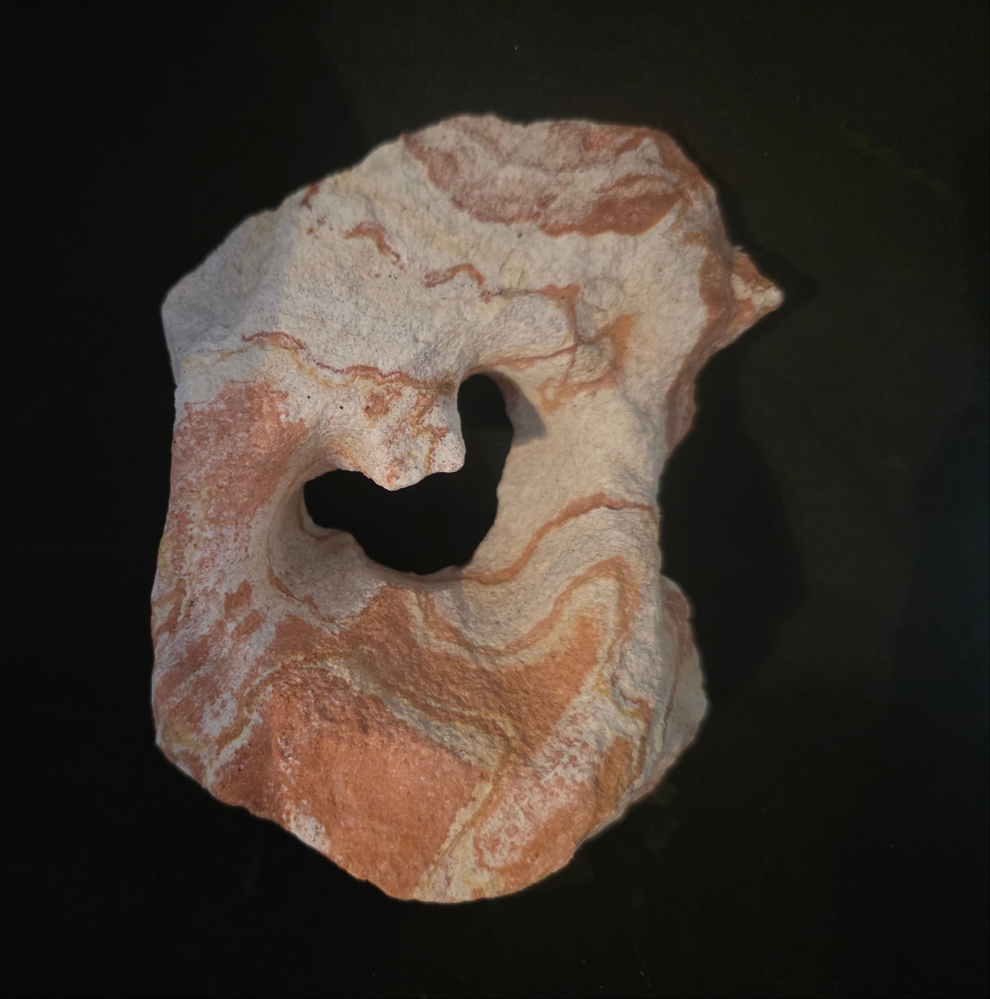 Decorative stone with a central hole on a black background