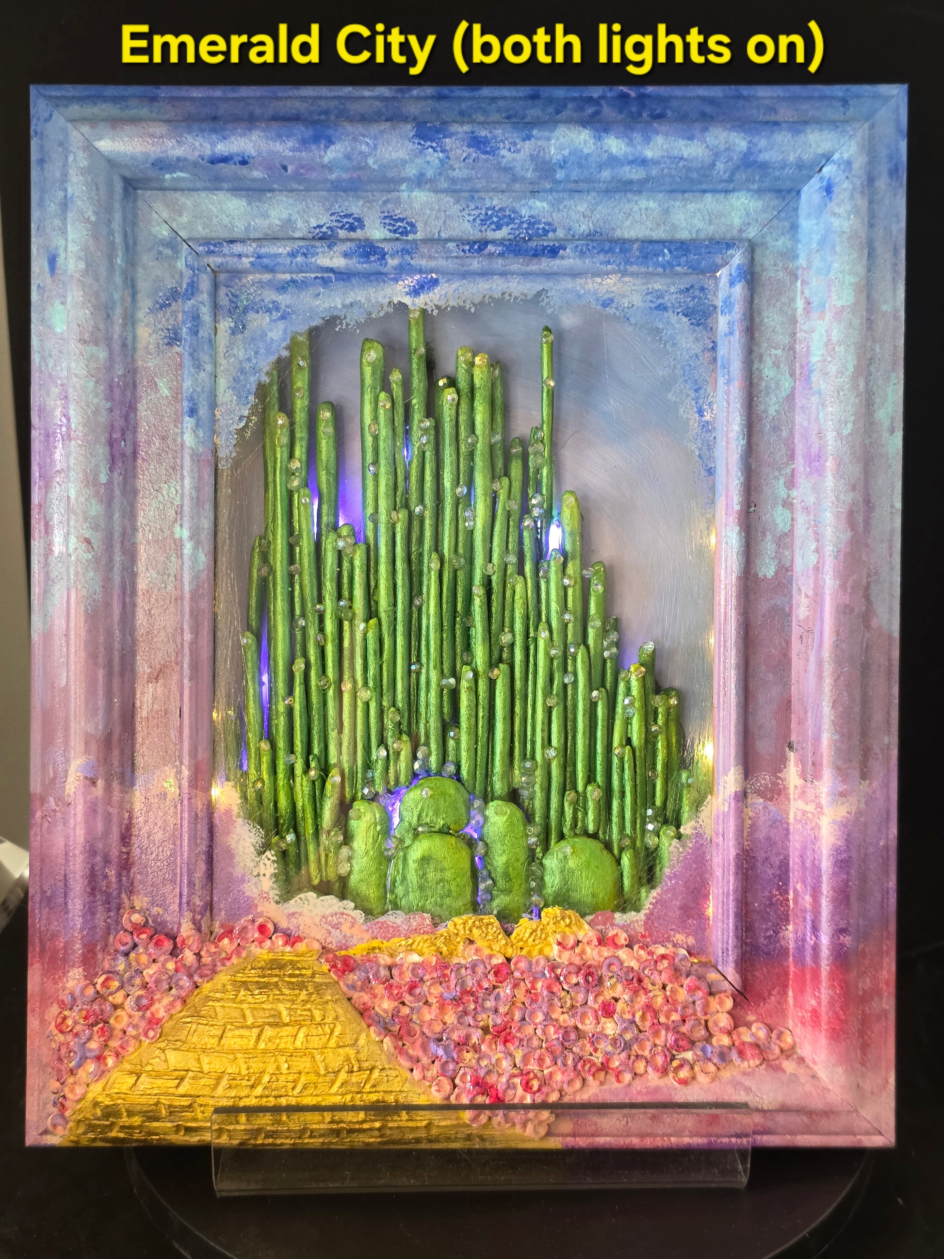 Wizard of Oz Emerald City shadow box with both warm white and purple fairy lights on, full illumination showing nightlight effect
