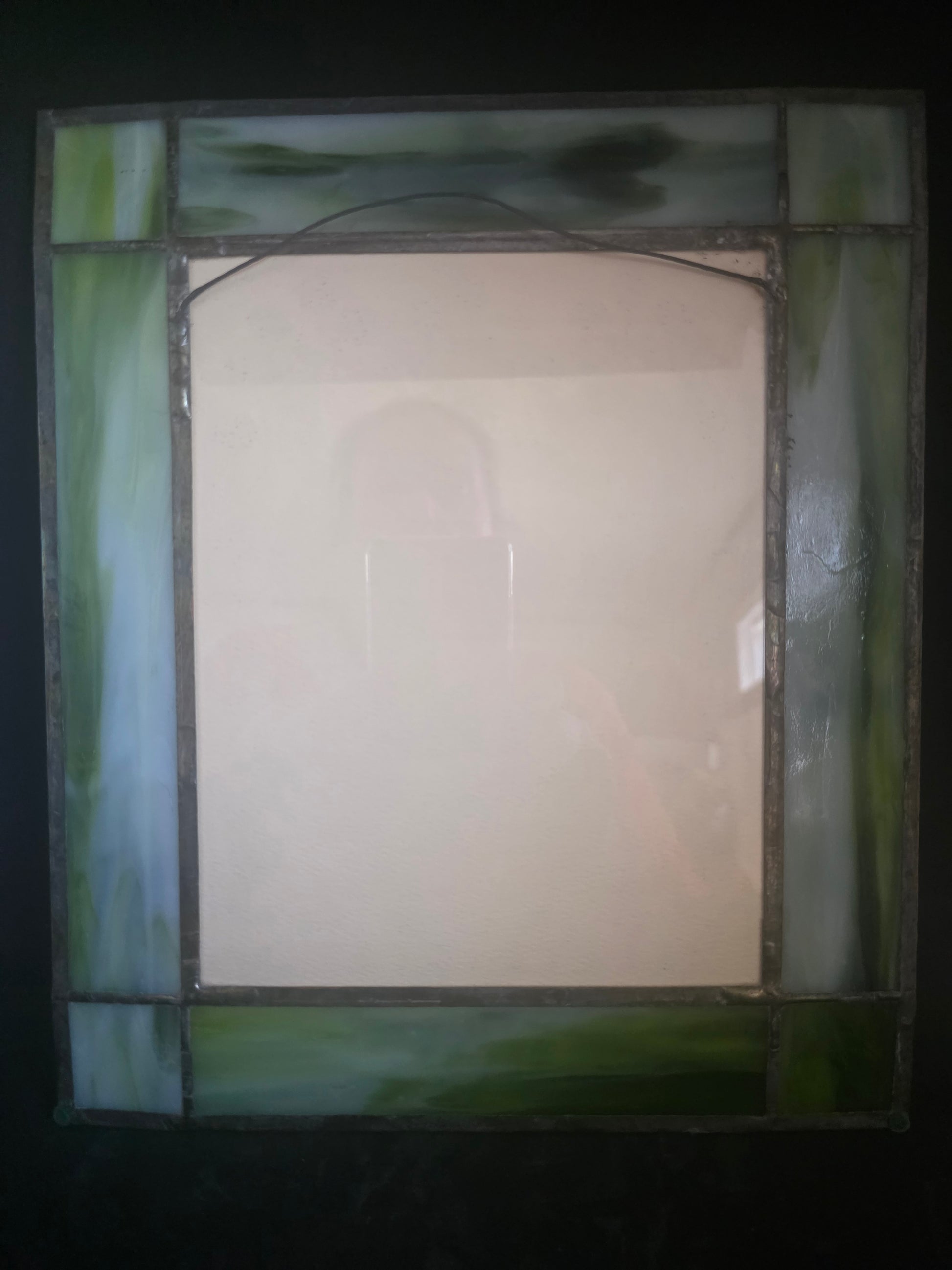 Rectangular stained glass panel with green border on a dark background