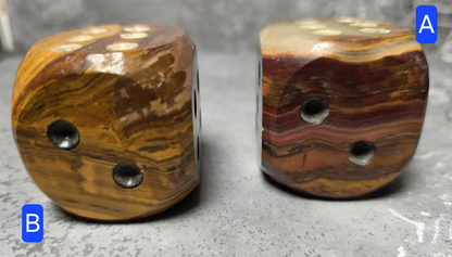 Two brown onyx dice with a textured surface on a gray background