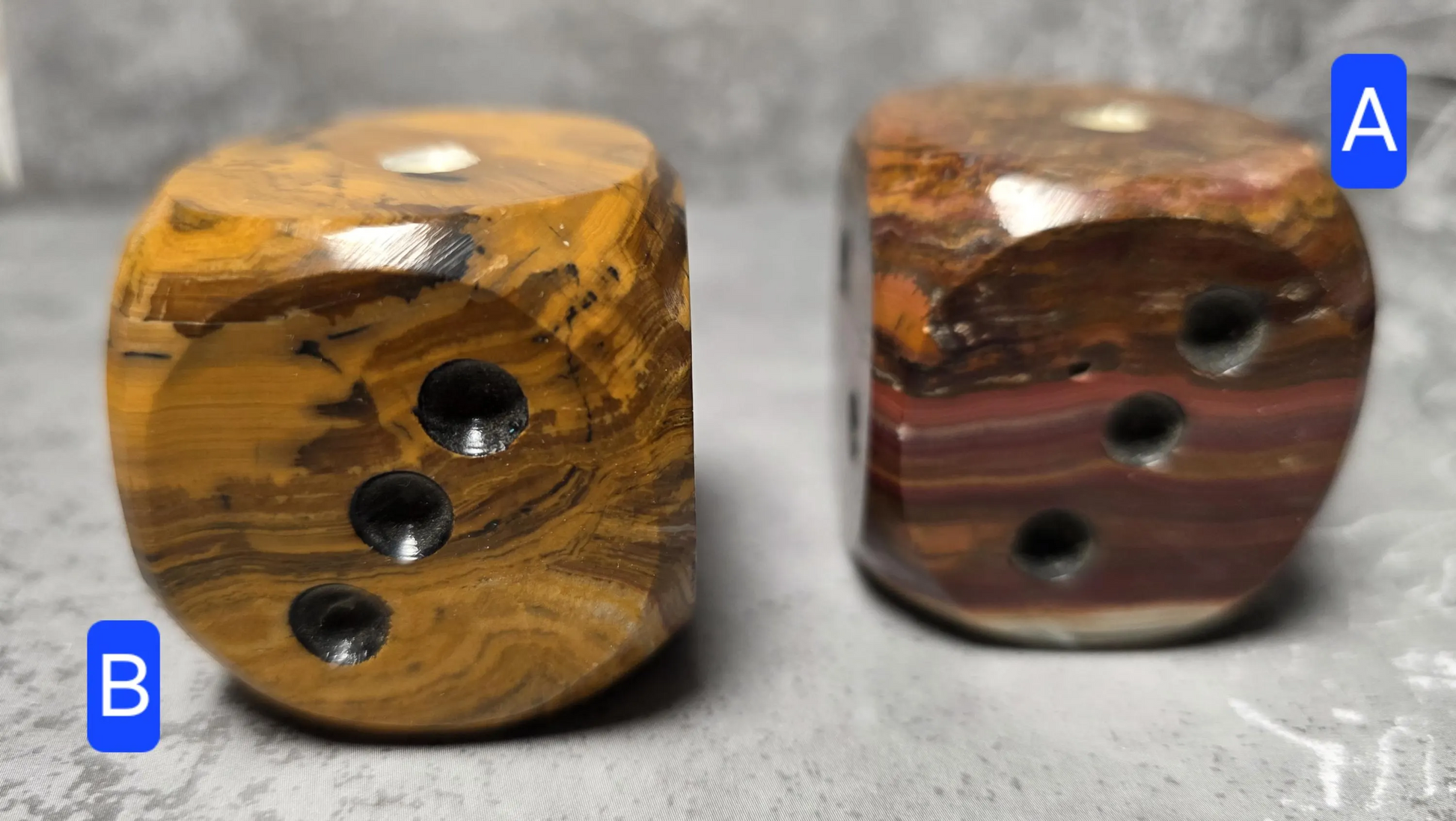 Two brown onyx dice with a textured surface on a gray background