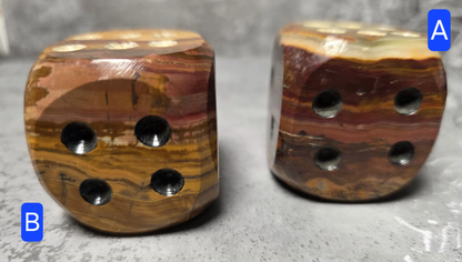Two brown onyx dice with a textured surface on a gray background