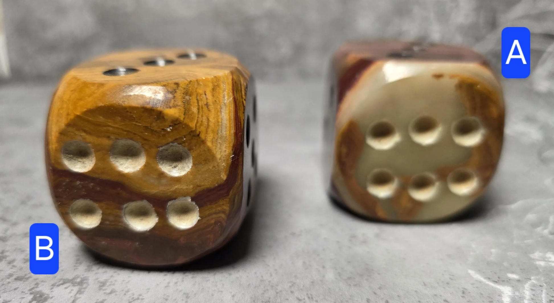 Two brown onyx dice with a textured surface on a gray background