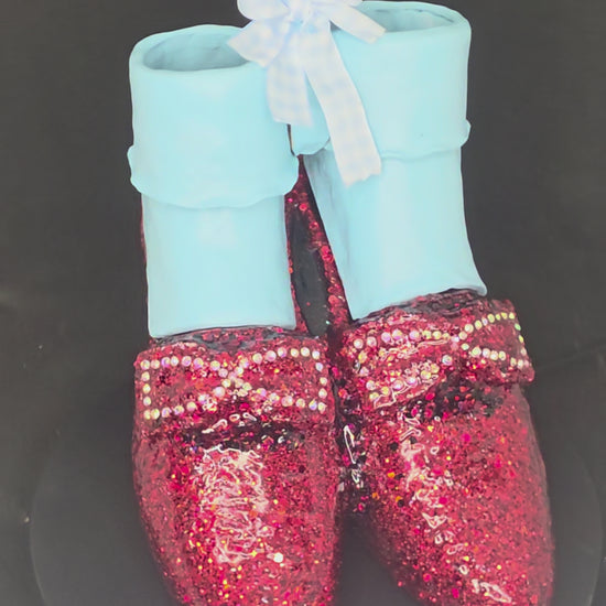 360-degree view of the Wizard of Oz Ruby Slippers mixed media sculpture, showing the glitter and rhinestone detail on the ceramic shoes, the removable polymer clay ankle socks, and the full sculptural form from all angles