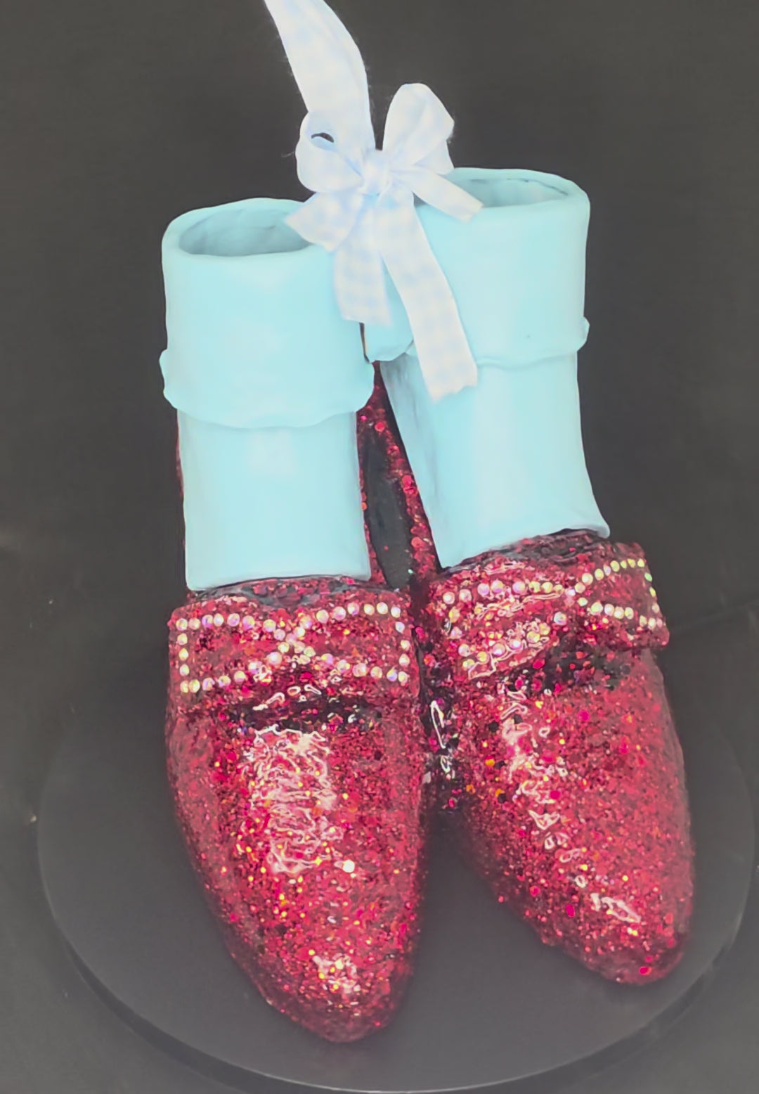 360-degree view of the Wizard of Oz Ruby Slippers mixed media sculpture, showing the glitter and rhinestone detail on the ceramic shoes, the removable polymer clay ankle socks, and the full sculptural form from all angles